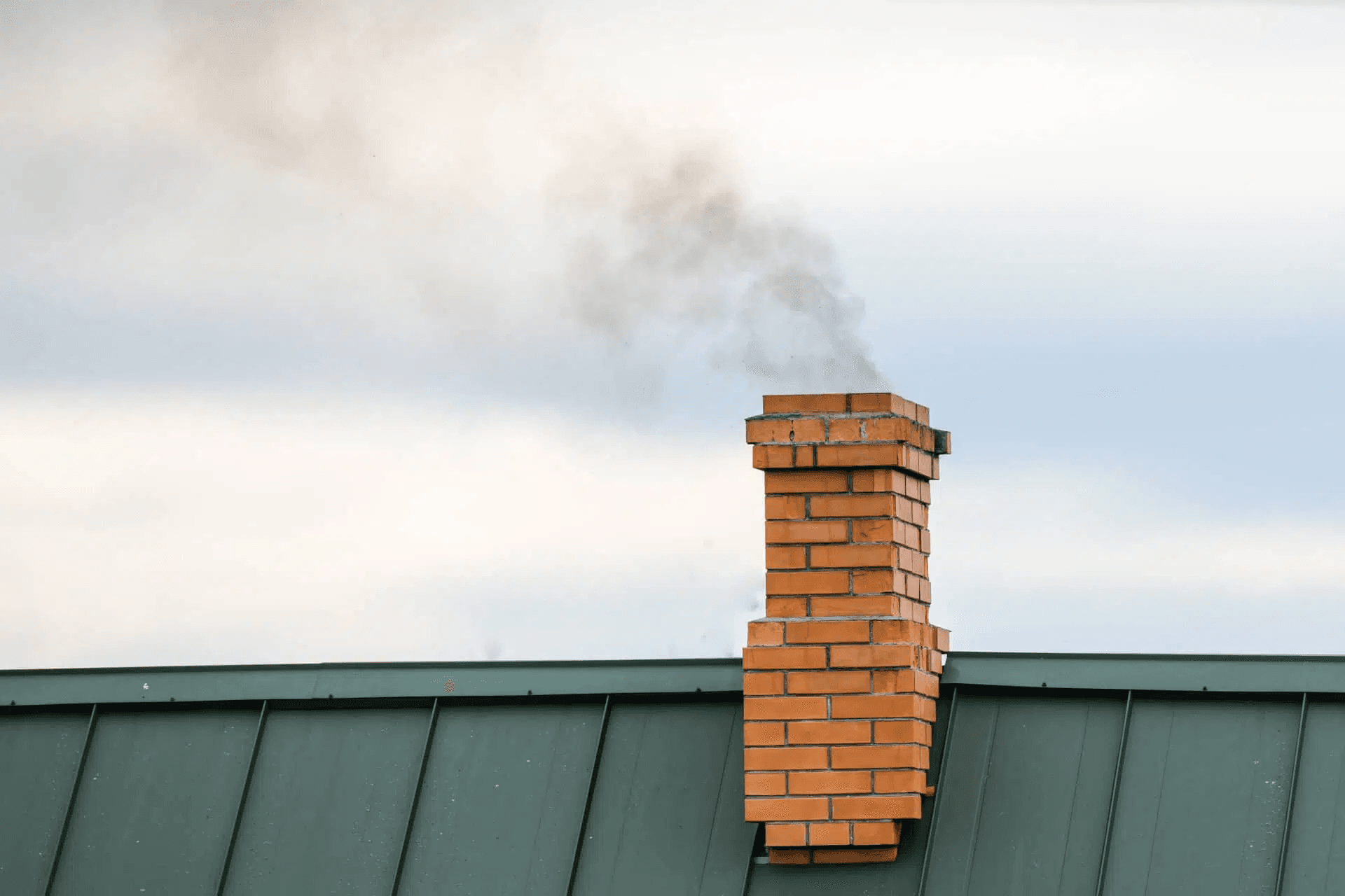 Brick chimney releasing smoke above a Florida roofline